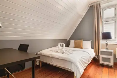 a bedroom with a bed and a desk and window at DINBNB Apartments l 50m to Bryggen l Multiple Apts l Balcony l View l Fireplace in Bergen