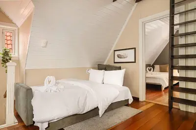 a bedroom with a white bed and a staircase at DINBNB Apartments l 50m to Bryggen l Multiple Apts l Balcony l View l Fireplace in Bergen