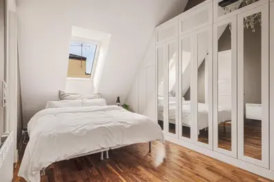a white bedroom with a bed and a mirror at DINBNB Apartments l 50m to Bryggen l Multiple Apts l Balcony l View l Fireplace in Bergen