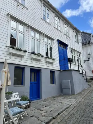 a white house with blue doors and a patio at Bergenshus rett ved Bryggen i Bergen in Bergen