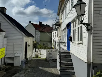 an alley in a town with white houses and blue doors at Bergenshus rett ved Bryggen i Bergen in Bergen