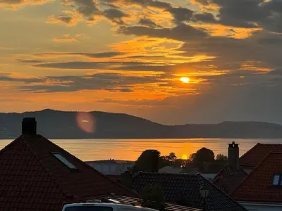 a sunset over the water with houses and roofs at Bergenshus rett ved Bryggen i Bergen in Bergen