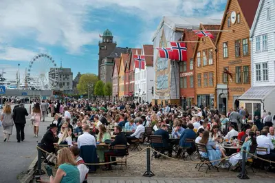 a crowd of people sitting at tables on a city street at Moderne Leilighet midt i Bykjernen Apt 1 in Bergen