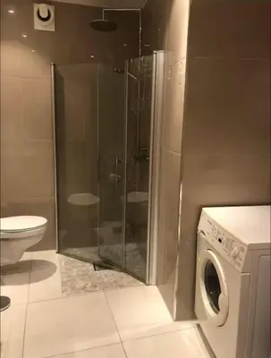 a bathroom with a shower and a washing machine at Moderne Leilighet midt i Bykjernen Apt 1 in Bergen