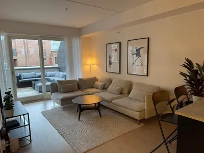 a living room with a couch and a table at Modern three-room apartment, private terrace and roof terrace in Trondheim
