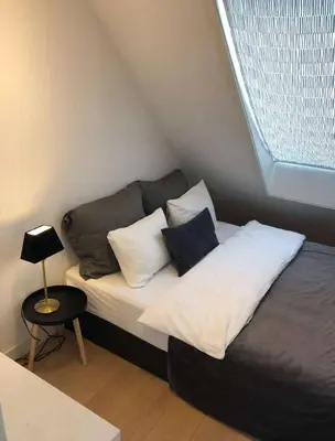 a bedroom with a bed with pillows and a window at Moderne Leilighet midt i Bykjernen in Bergen