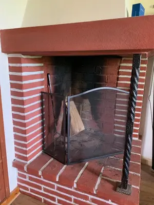 a brick fireplace with a glass screen in it at Landlige Peru in Ringsaker