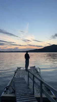 a man standing on a dock in the water at En Perle ved Masfjorden in Masfjorden
