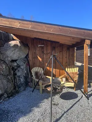 a wooden cabin with two chairs and a fireplace at Drøm deg bort til fjells Velkommen til en perle av en hytte in Masfjorden
