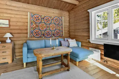 a living room with a blue couch and a table at Atmospheric Log Cabin By Myllavannet