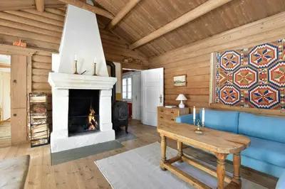 a living room with a fireplace and a blue couch at Atmospheric Log Cabin By Myllavannet