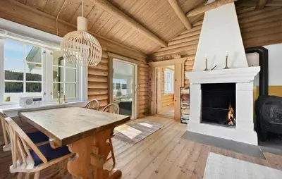 a dining room with a fireplace in a log cabin at Atmospheric Log Cabin By Myllavannet