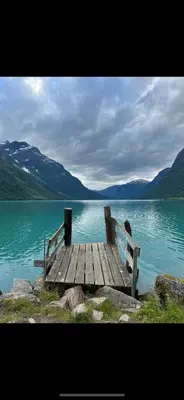 a wooden bench sitting on the edge of a lake at Faleide Grandview in Stryn