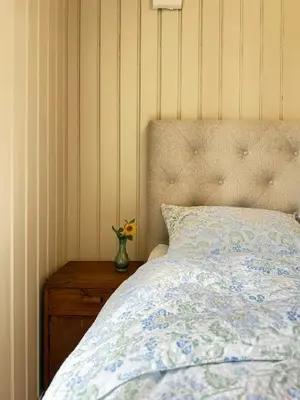 a bedroom with a bed and a vase of flowers on a table at Historic Croft With Views Over Lake Mjøsa in Ottestad