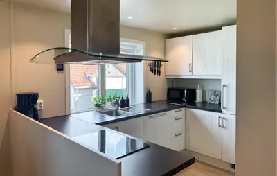 a kitchen with white cabinets and a black counter top at 2 Bedroom Cozy Apartment In Laksevåg in Bergen