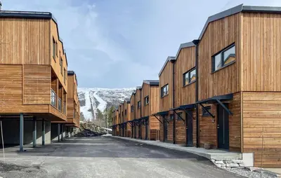 a row of wooden buildings with a mountain in the background at Amazing Apartment In Bjorli in Bjorli