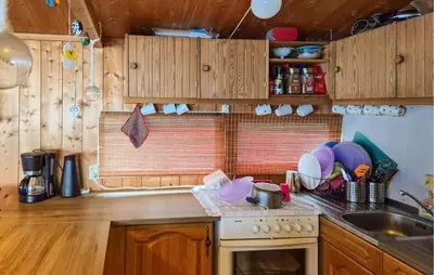 a kitchen with wooden cabinets and a stove and a sink at Nice Home In Hatlestrand With Wifi in Hatlestrand