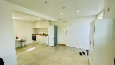 a kitchen with white cabinets and a refrigerator at Cosy One Bedroom Apartment in Hval