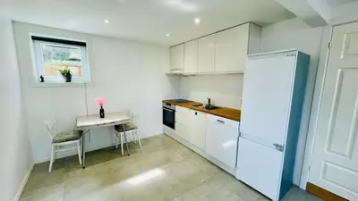 a kitchen with a table and a white refrigerator at Cosy One Bedroom Apartment in Hval