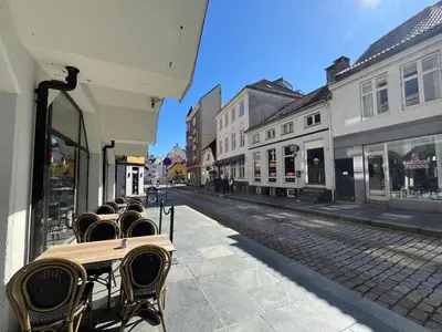 an empty street with tables and chairs on a sidewalk at Modern Apartment Vaskerelven 12 in Bergen