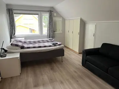 a room with a bed and a couch and a window at Loft apartment with 3 bedrooms in Trondheim