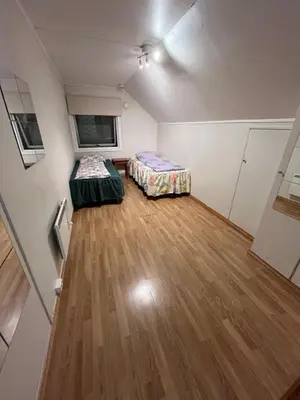 an empty room with two beds and a wooden floor at Loft apartment with 3 bedrooms in Trondheim