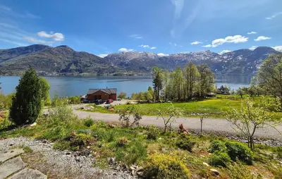a house on the shore of a lake with mountains at 4 Bedroom Stunning Home In Tørvikbygd in Tyrvikbygd