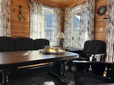 a dining room with a table and chairs and windows at Cozy cabin in Eikedalen in Eikedalen