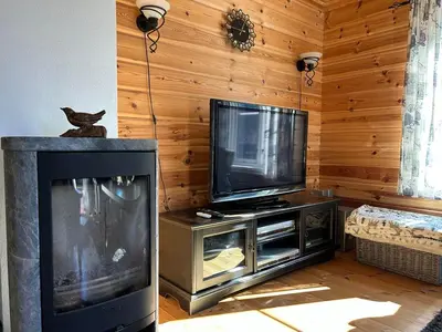a living room with a fireplace and a tv at Cozy cabin in Eikedalen in Eikedalen
