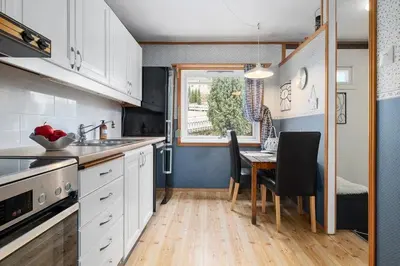 a kitchen with white cabinets and a table with chairs at FjordNest Årdalstangen in Årdalstangen