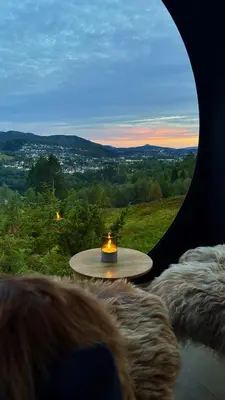 a woman looking out a window at a table with a candle at Birdbox Bergen in Bergen