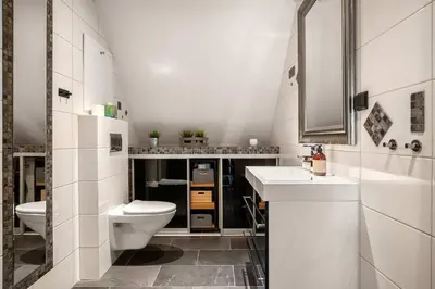 a white bathroom with a toilet and a sink at DINBNB Apartments l 200m to Bryggen l Luxury 2 BR l 2min to Floibanen in Bergen