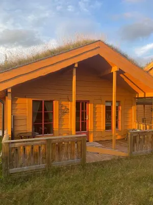a wooden house with a fence in front of it at Adventurous cabin cozy on Sjusjøen with sauna! in Sjusjøen
