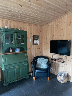 a room with a green cabinet and a chair and a television at Adventurous cabin cozy on Sjusjøen with sauna! in Sjusjøen