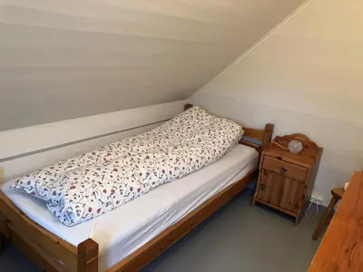 a small bedroom with a bed and a night stand at Seaside apartment in farmhouse close to nature in Husevåg