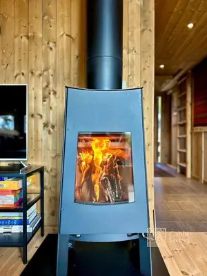 a fire in a stove in a room with a tv at Modern mountain cabin Ski in-out 2 Bathrooms in Ringsaker