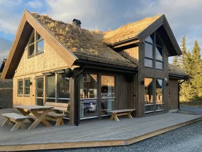a house with a roof with a picnic table and benches at Family Cabin With A View Of Skeikampen in Svingvoll