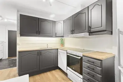 a kitchen with black cabinets and white appliances at Staymate apartments. Trondheim sentrum in Trondheim