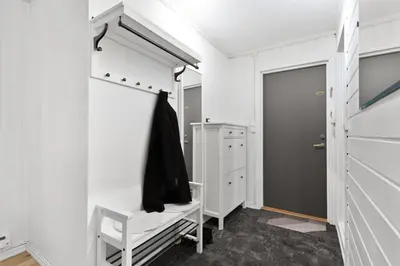 a white bathroom with a chair and a closet at Staymate apartments. Trondheim sentrum in Trondheim