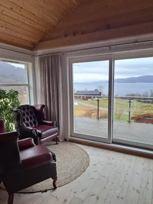 a living room with two chairs and large windows at Stort hus med havutsikt ved fjord og fjell med båt in Lensvik