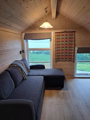 a living room with a couch and a large window at Stort hus med havutsikt ved fjord og fjell med båt in Lensvik