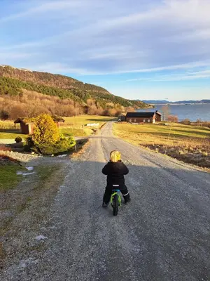 a young child riding a bike down a road at Stort hus med havutsikt ved fjord og fjell med båt in Lensvik