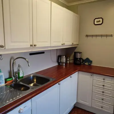 a kitchen with white cabinets and a sink at Leilighet nær E4 i sentrum av Eina in Eina