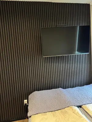 a bedroom with a wall with a tv and a bed at CozyStay Beside Historic Bryggen in Bergen