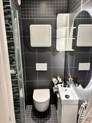 a black tiled bathroom with a toilet and a sink at CozyStay Beside Historic Bryggen in Bergen