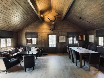 a living room with wooden ceilings and tables and chairs at Dream cabin by Geilo, ski-in ski-out with room for the whole family in Geilo