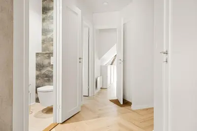 a bathroom with a toilet and a hallway with white walls at Bergen City Living in Bergen
