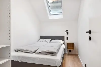a bedroom with a bed with white sheets and a window at Newly renovated apartment in the heart of Bergen city center in Bergen