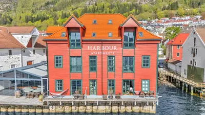 an orange building on the water next to a dock at Heimby - Seaside View Luxury - Free Parking in Bergen