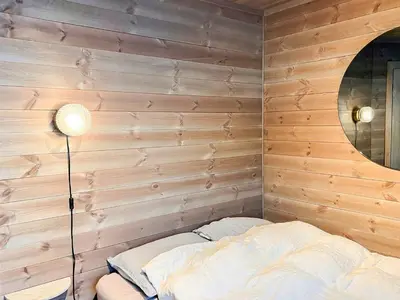 a bedroom with a wooden wall with a bed and a lamp at Modern Family Cabin By Tempelseter Ski Trails in Eggedal